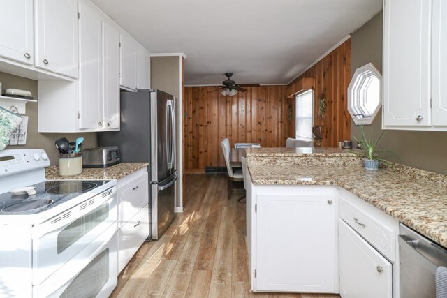 623 Bendle Ave, Shelby, OH 44875 - kitchen with stainless steel appliances, a ceiling fan, wood walls, white cabinetry, and light wood-style flooring
