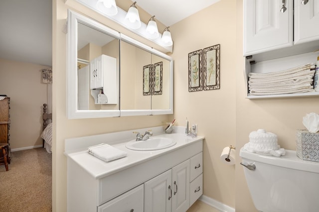 bathroom featuring toilet, vanity, and baseboards