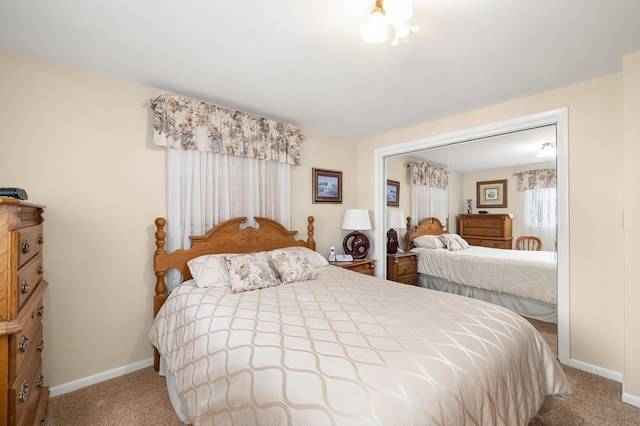 carpeted bedroom with a closet and baseboards