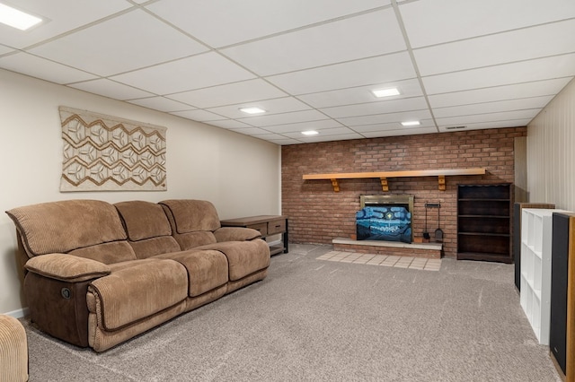 living room with a drop ceiling, carpet, brick wall, and a fireplace