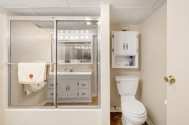 bathroom featuring vanity, baseboards, an enclosed shower, a paneled ceiling, and toilet