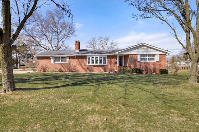 ranch-style house with brick siding, a chimney, and a front yard