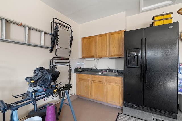 kitchen featuring a sink, black fridge with ice dispenser, dark countertops, and finished concrete floors