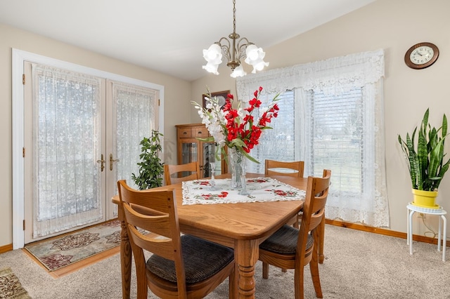 dining room featuring lofted ceiling, french doors, carpet, an inviting chandelier, and baseboards