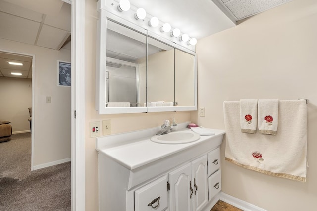 bathroom with vanity, a paneled ceiling, and baseboards