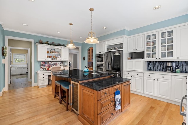 kitchen with white cabinetry, open shelves, light wood-type flooring, a kitchen island, and appliances with stainless steel finishes