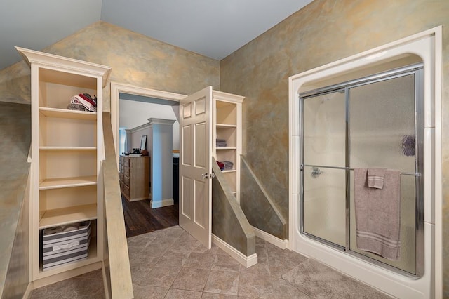 full bathroom featuring a walk in closet, lofted ceiling, a shower stall, tile patterned floors, and built in features
