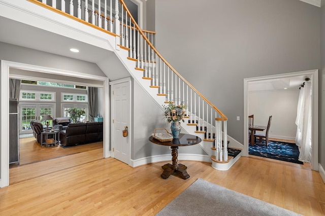 staircase featuring a high ceiling, baseboards, and wood finished floors