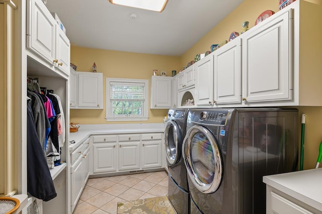 clothes washing area featuring light tile patterned flooring, cabinet space, and washing machine and dryer