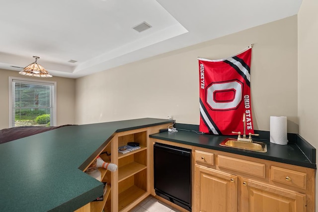 kitchen featuring a sink, a raised ceiling, fridge, light tile patterned floors, and dark countertops