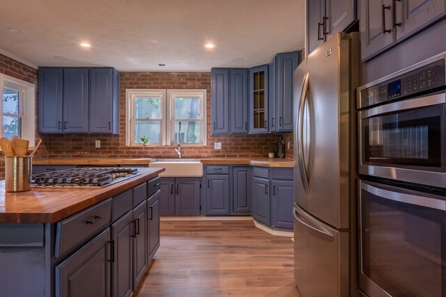 1676 Old Delaware Rd, Mount Vernon, OH 43050 - kitchen with stainless steel appliances, butcher block counters, light wood-style floors, glass insert cabinets, and backsplash