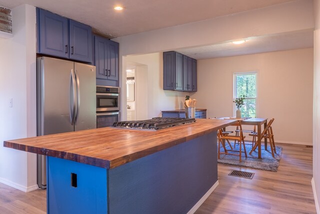 1676 Old Delaware Rd, Mount Vernon, OH 43050 - kitchen featuring butcher block counters, stainless steel appliances, blue cabinets, light wood-style flooring, and a kitchen island