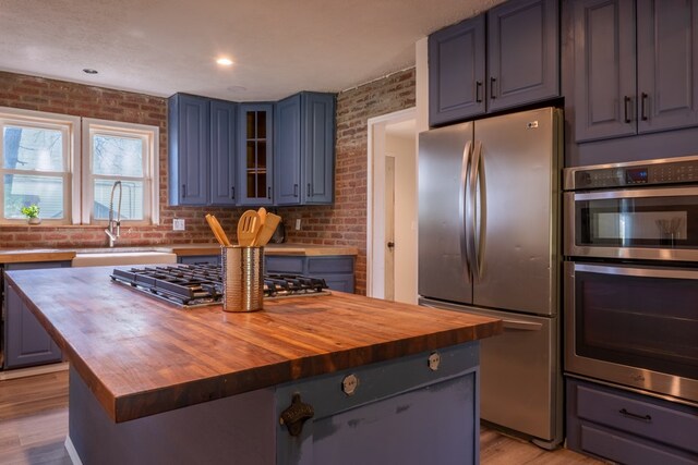 1676 Old Delaware Rd, Mount Vernon, OH 43050 - kitchen featuring wood counters, stainless steel appliances, brick wall, a kitchen island, and glass insert cabinets