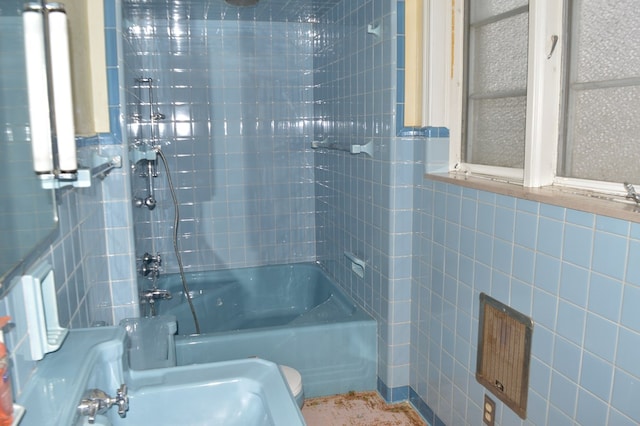 bathroom with shower / bathing tub combination and tile walls