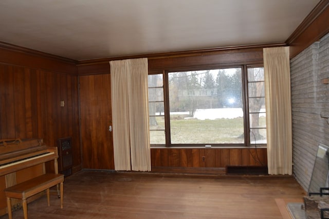 misc room with wood-type flooring, wooden walls, and ornamental molding