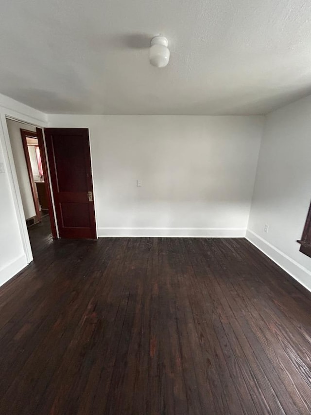 unfurnished room with dark wood-type flooring and a textured ceiling