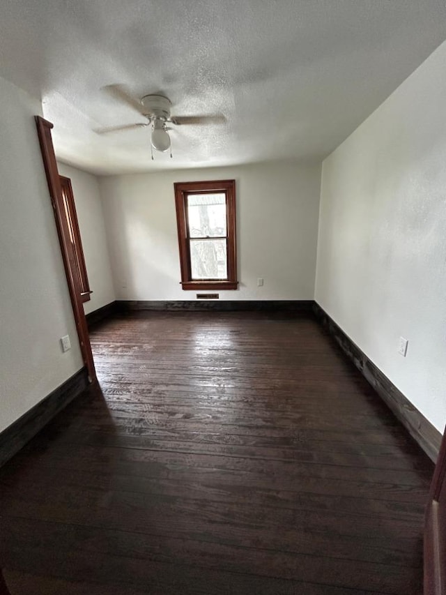 empty room featuring dark wood-type flooring, ceiling fan, and a textured ceiling