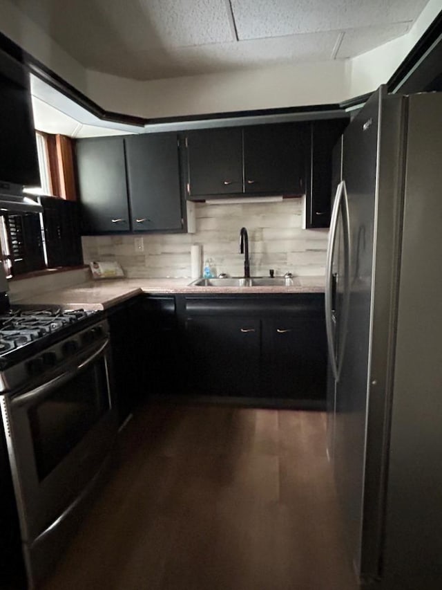 kitchen with appliances with stainless steel finishes, dark hardwood / wood-style floors, sink, and decorative backsplash