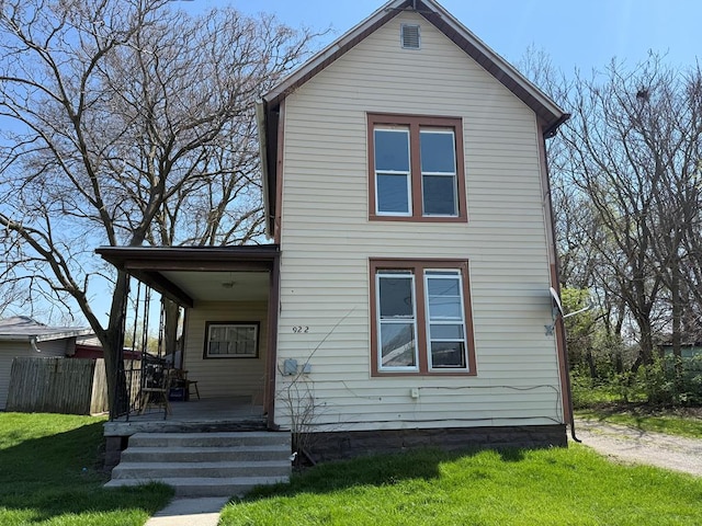 traditional-style home featuring a porch, fence, and a front lawn