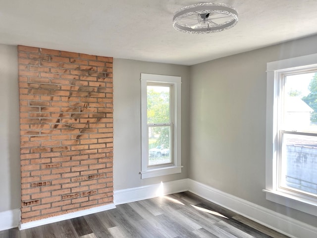 unfurnished room with plenty of natural light, dark hardwood / wood-style flooring, and a textured ceiling