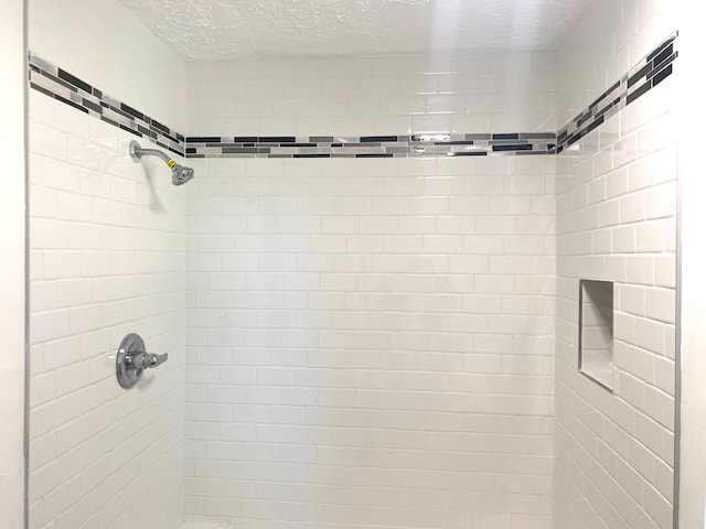 bathroom featuring a tile shower and a textured ceiling