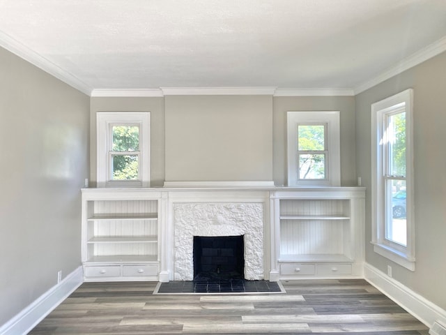 unfurnished living room with wood-type flooring, a stone fireplace, and crown molding