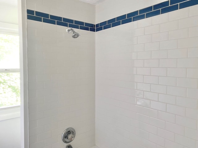 bathroom with a healthy amount of sunlight and tiled shower / bath