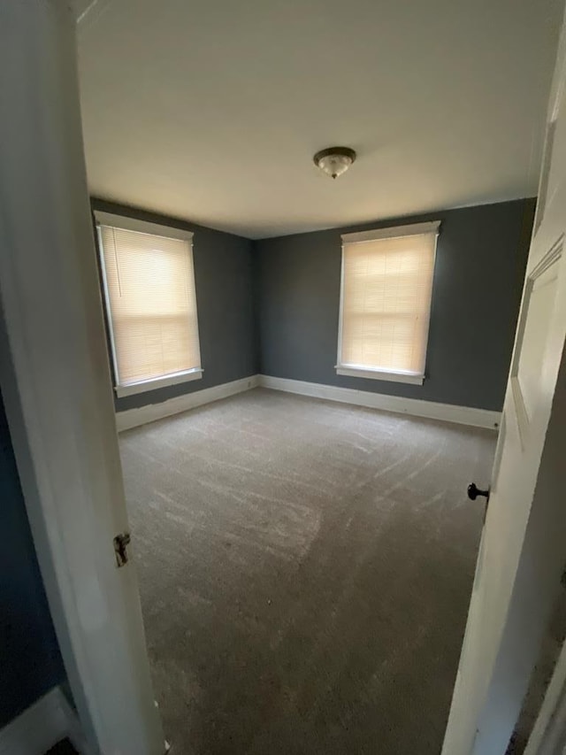 spare room featuring baseboards, a healthy amount of sunlight, and light carpet