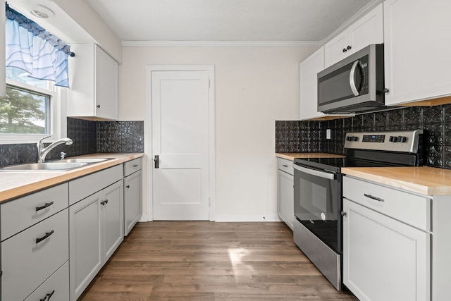 110 Hill St, Edison, OH 43320 - kitchen featuring appliances with stainless steel finishes, ornamental molding, wood finished floors, decorative backsplash, and white cabinets