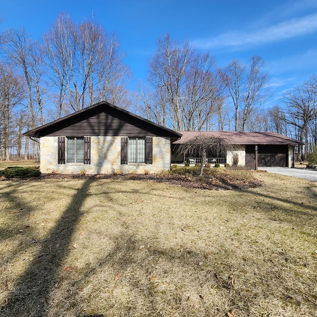 view of front of home featuring driveway, a carport, a front lawn, and stone siding