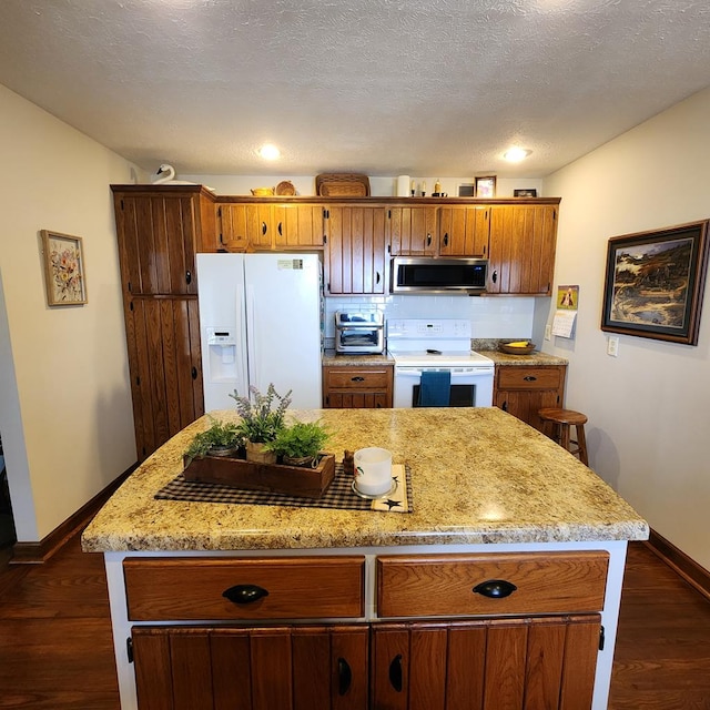 kitchen featuring dark wood-style floors, white appliances, brown cabinetry, and a textured ceiling