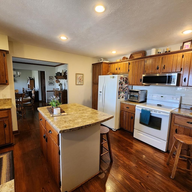 kitchen with a center island, white appliances, brown cabinets, and dark wood finished floors