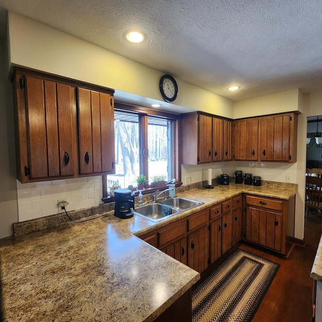 kitchen featuring backsplash, a textured ceiling, dark wood finished floors, and a sink