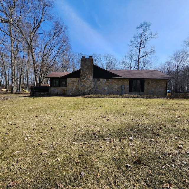 exterior space featuring stone siding, a yard, and a chimney