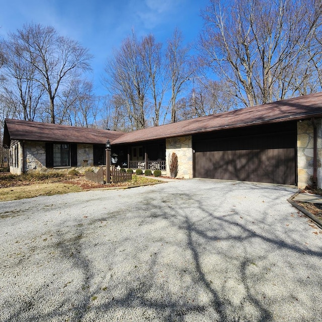 view of front facade with a garage, stone siding, and aphalt driveway