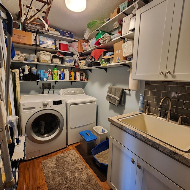 laundry room featuring a sink, wood finished floors, washing machine and clothes dryer, and cabinet space