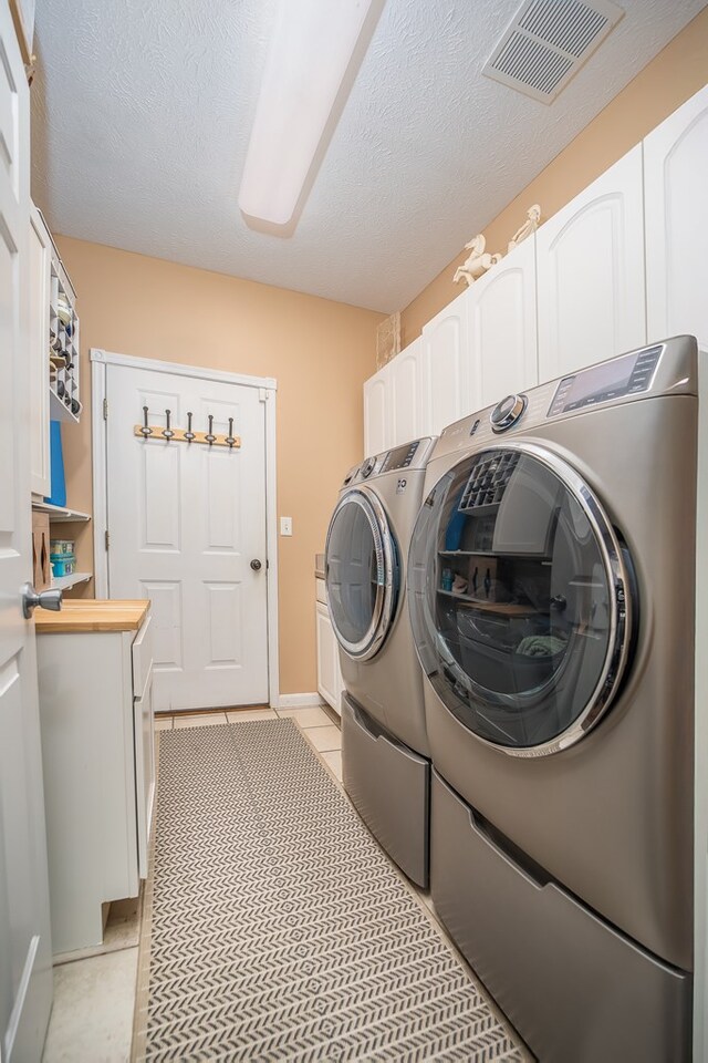 2453 Whitney Ave, Ontario, OH 44906 - laundry area with washer and clothes dryer, cabinet space, a textured ceiling, and light tile patterned flooring