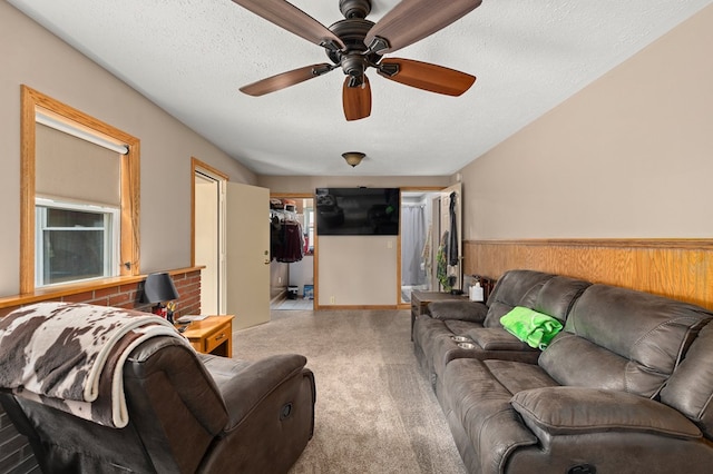 living room featuring wood walls, ceiling fan, and a textured ceiling