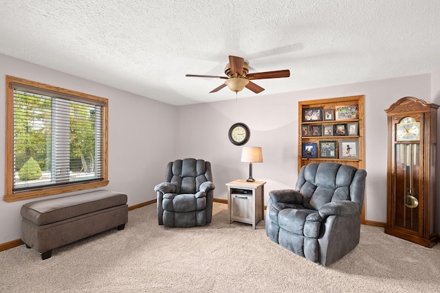 sitting room with ceiling fan, carpet floors, and a textured ceiling