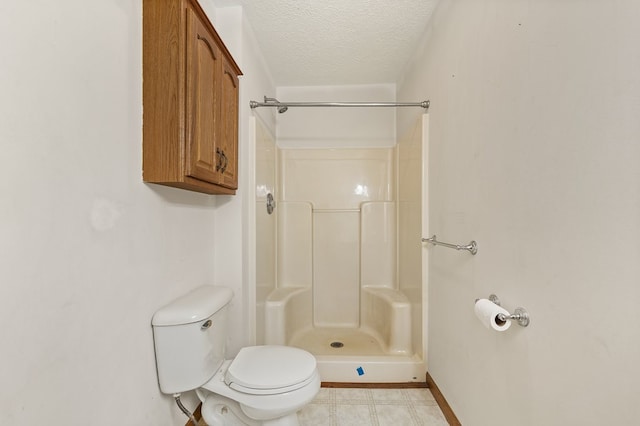 bathroom with a textured ceiling, toilet, and walk in shower