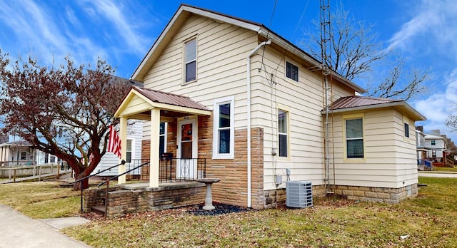 view of front of home with a front yard, central AC, metal roof, and fence