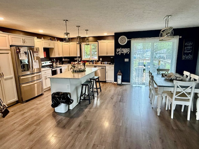 950 Woodbine St, Willard, OH 44890 - kitchen featuring appliances with stainless steel finishes, light wood-type flooring, light countertops, decorative light fixtures, and a kitchen island