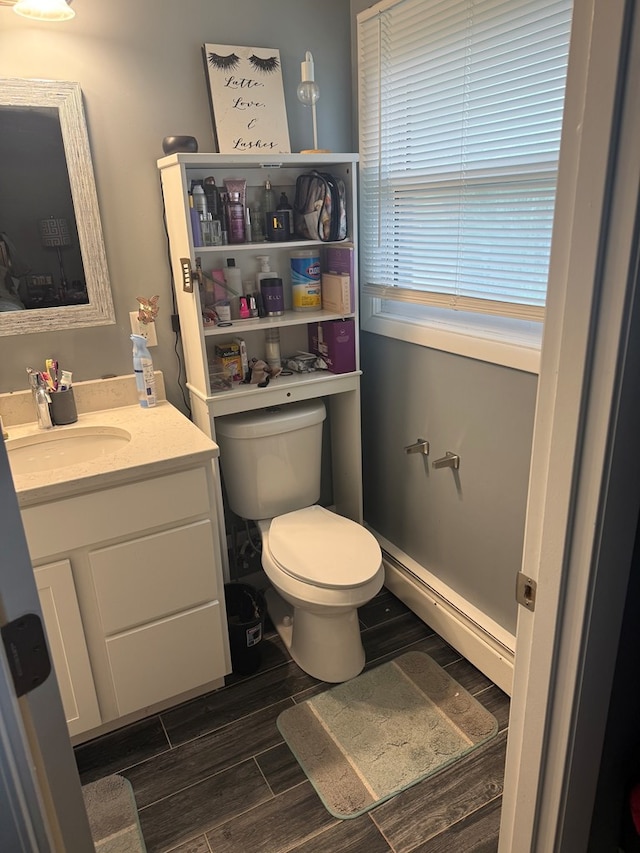 950 Woodbine St, Willard, OH 44890 - half bath with wood finish floors, toilet, vanity, and a baseboard radiator