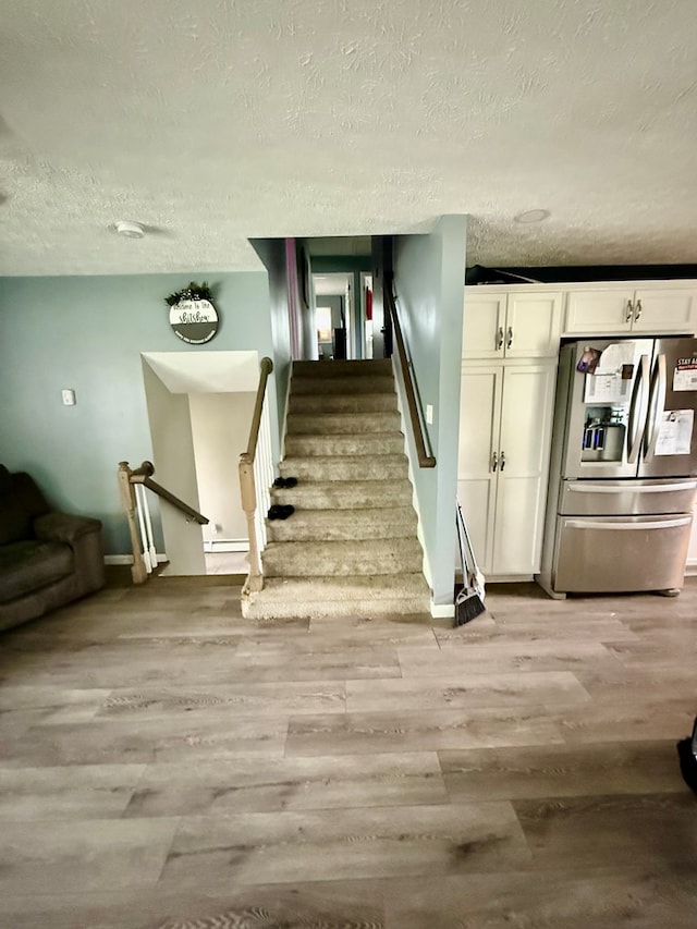 950 Woodbine St, Willard, OH 44890 - staircase with a textured ceiling, wood finished floors, baseboards, and baseboard heating