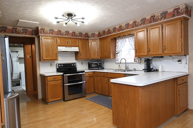 kitchen with kitchen peninsula, sink, stainless steel appliances, and a textured ceiling