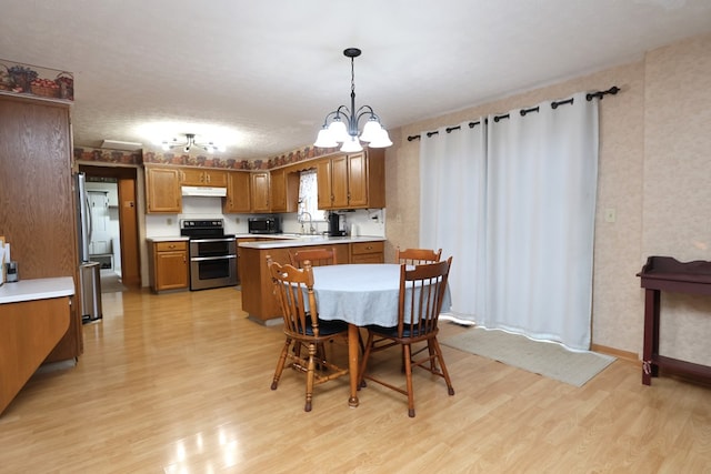 dining room with sink, light wood-type flooring, a textured ceiling, and a chandelier