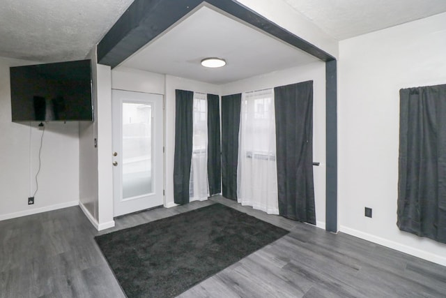 foyer entrance featuring dark hardwood / wood-style flooring, beamed ceiling, and a textured ceiling