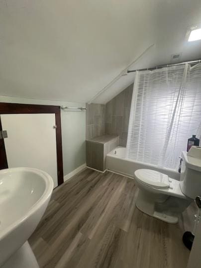 379 S Main St, Mansfield, OH 44902 - full bathroom featuring toilet, lofted ceiling, wood finished floors, shower / bathtub combination with curtain, and baseboards