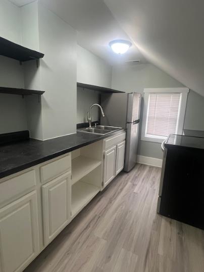 379 S Main St, Mansfield, OH 44902 - kitchen featuring open shelves, a sink, lofted ceiling, light wood-style flooring, and dark countertops