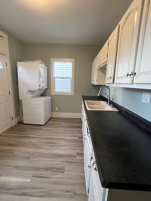 379 S Main St, Mansfield, OH 44902 - kitchen with a sink, stacked washer / drying machine, dark countertops, baseboards, and light wood finished floors